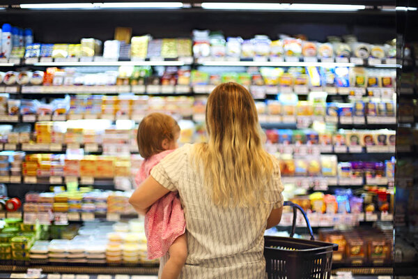 Cheerful mother and baby spending time in shopping in supermarket, shallow depth of field 