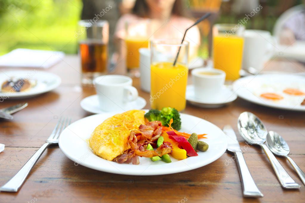 Omelet with pepper, cucumber, bakon and salad on the table outdoors