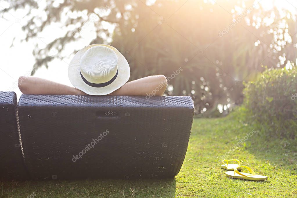 Relaxed woman in the hat sitting at the beach at sunset time
