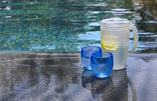 在无边泳池边的柠檬和罐子的水的玻璃 — 图库照片
