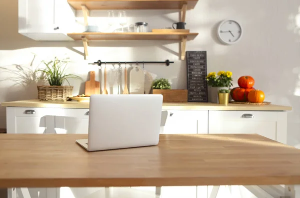 Closeup of laptop on kitchen counter. Kitchen on background