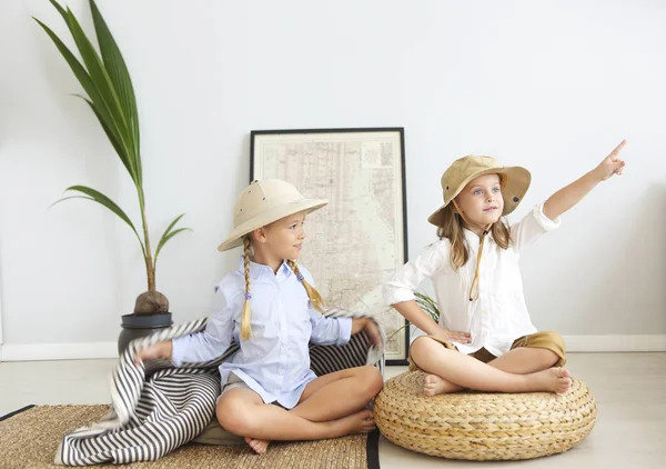 Two little girls are playing at home to travelers with bengal cat wearing vintage style clothes. Childhood, fantasy, imagination