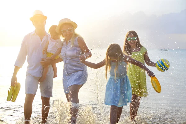 快乐的年轻家庭在海滩上玩耍 在日落时跳跃 — 图库照片