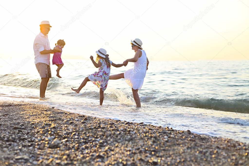 Happy young family have fun on beach run and jump at sunset 
