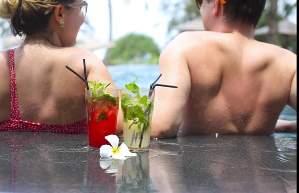 年轻的微笑的夫妇与饮料酒精鸡尾酒在游泳池附近 — 图库照片