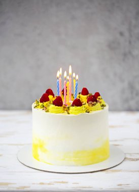 Ahududu, Antep fıstığı ve mumlar kek standında güzel mutlu doğum günü pastası mascarpone ile süslenmiş 