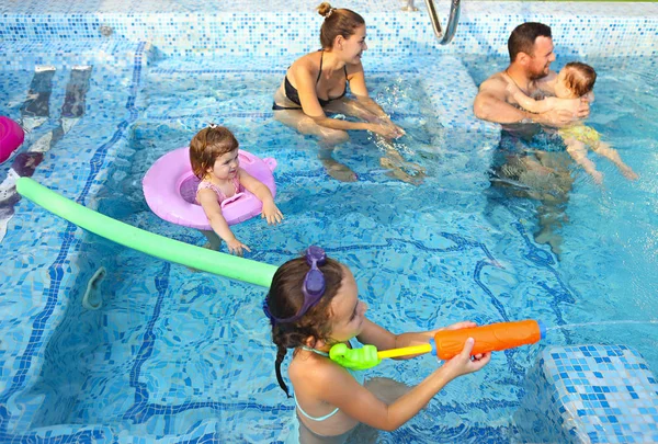 プールで一緒に楽しんで小さな子供たちと幸せな若い家族 — ストック写真