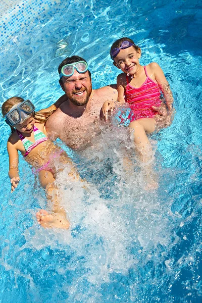 アクティブな家族の幸せ 若いお父さんと小さな娘の夏休みを楽しんでいるスイミング プールで溶射 — ストック写真