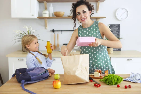 Bella bruna madre e sua figlia imballaggio pranzo sano — Foto Stock