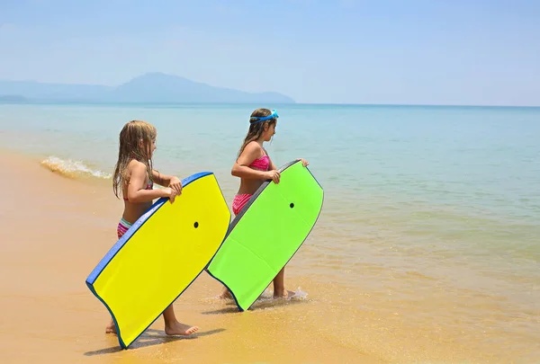 熱帯の海のビーチで遊んでサーフィン ボードと小さな女の子 — ストック写真