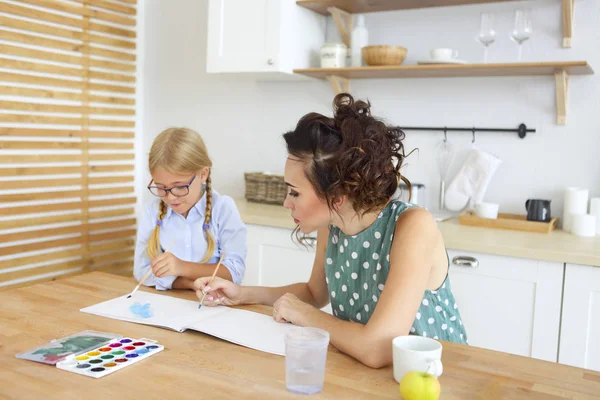 Mother and daughter painting together at home on the kitchen — Stock Photo, Image