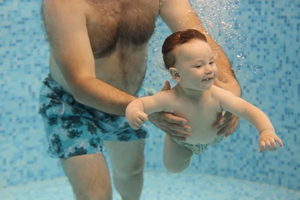 Padre enseñando a un niño pequeño a nadar bajo el agua en la piscina — Foto de Stock