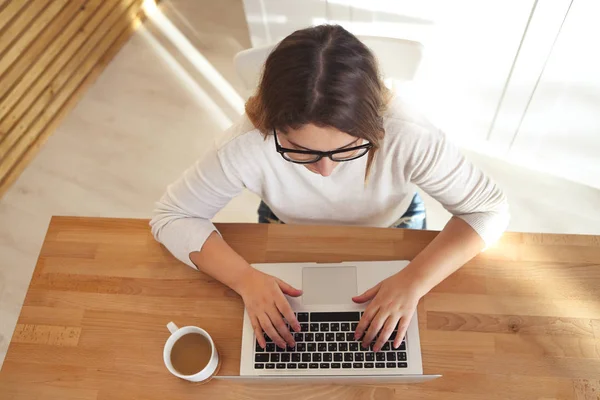 Draufsicht von Frauenhänden beim Tippen auf der Laptop-Tastatur mit Brille — Stockfoto