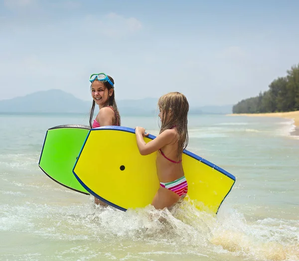 Kislányok a szörf deszkák játszik a trópusi ocean beach — Stock Fotó