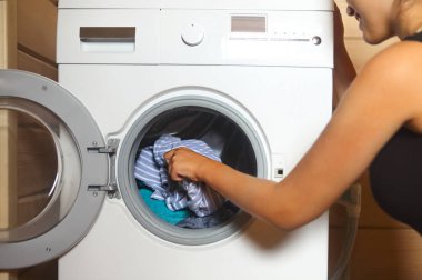 Çamaşır makinesinden çamaşır alan genç bir kadın. 