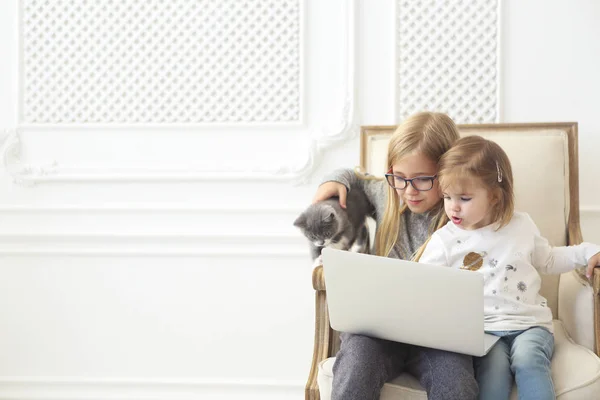 Adorable litle sisters using their computer laptop together with — Stock Photo, Image