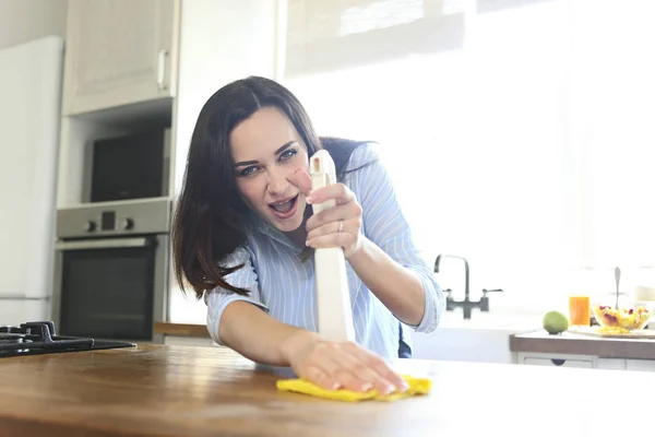 Woman with rag and spray bottle cleaning wooden counter-top — Stock Photo, Image