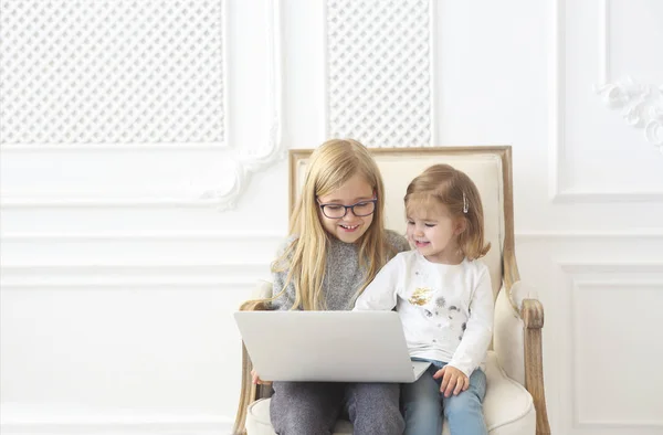 Two adorable litle sisters using their computer laptop together — Stock Photo, Image
