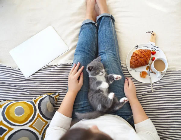 Young woman with cute little kitten sitting on bed at home havin — Stock Photo, Image