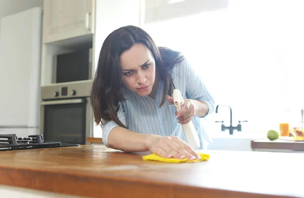 Donna con straccio e bottiglia spray pulizia piano di lavoro in legno — Foto Stock