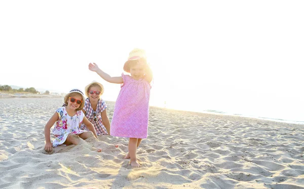 Счастливая девочка и ее сестры играют в песок на красивой b — стоковое фото