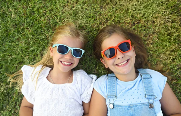 Laughing children wearing sunglasses relaxing during summer day — Stock Photo, Image