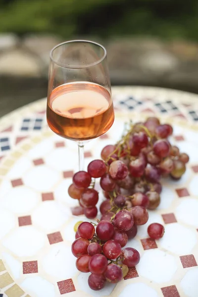 One glass of rose wine in autumn vineyard on marble table