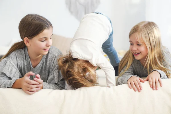 Drie gelukkige kleine zusters op een bed — Stockfoto