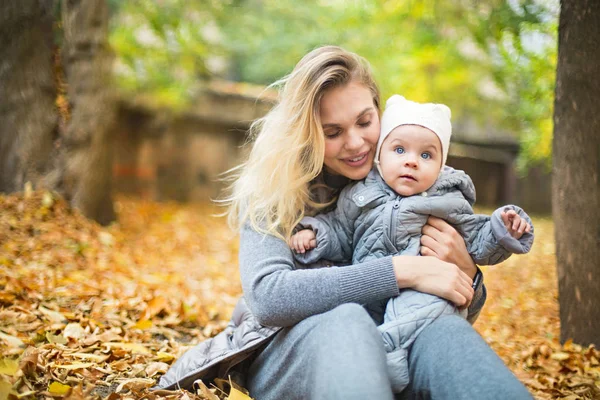 Moeder en haar kleine dochter spelen knuffelen op de herfstwandeling in n — Stockfoto