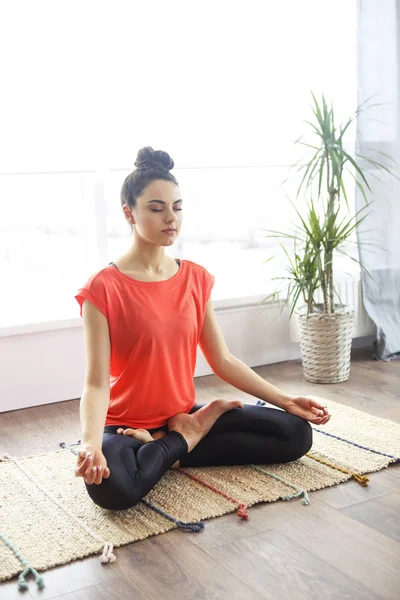 Attraente giovane donna che esercita e seduto in yoga loto posi — Foto Stock