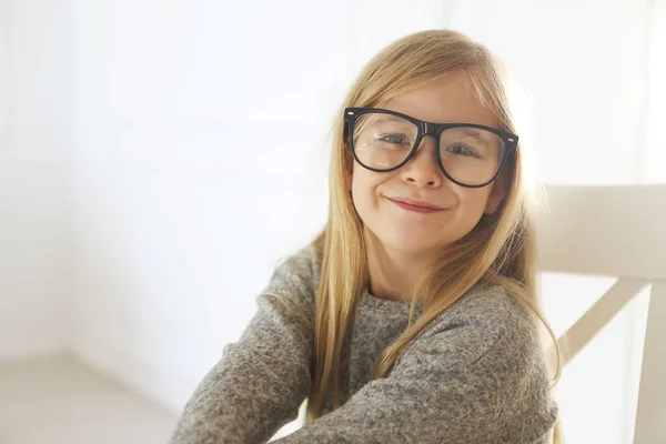 Glimlachend schattig klein meisje met zwarte bril over witte ondergrond — Stockfoto