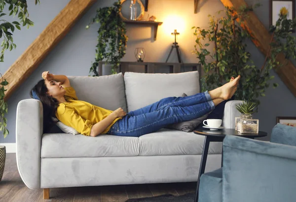 Young brunette woman relaxing on the couch after a long day — Stock Photo, Image