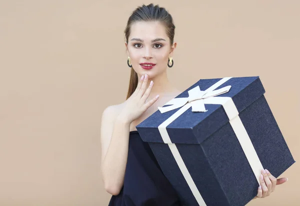 Cute girl in navy blue clothes holding big gift box — Stock Photo, Image