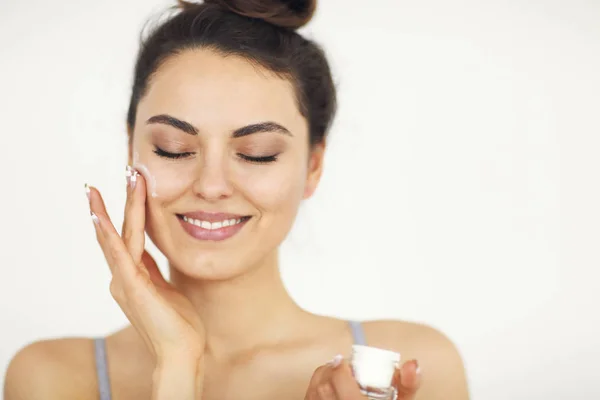 Mujer joven aplicando crema facial en la piel perfecta — Foto de Stock