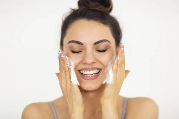 Schöne junge kaukasische Frau wäscht ihr Gesicht mit Schaum — Stockfoto
