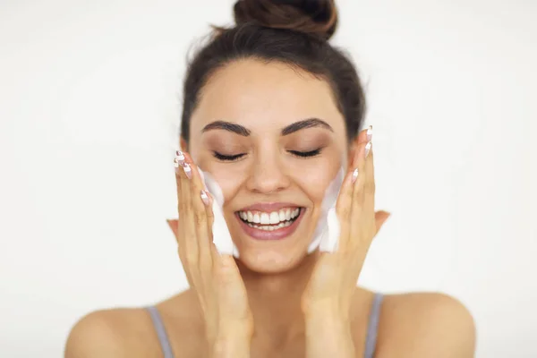 Beautiful young caucasian woman washing her face with foam — Stock Photo, Image