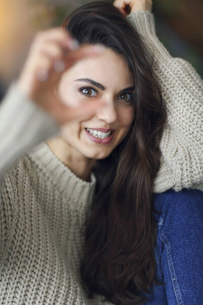 Portrait of a young happy beautiful woman in warm clothings at h
