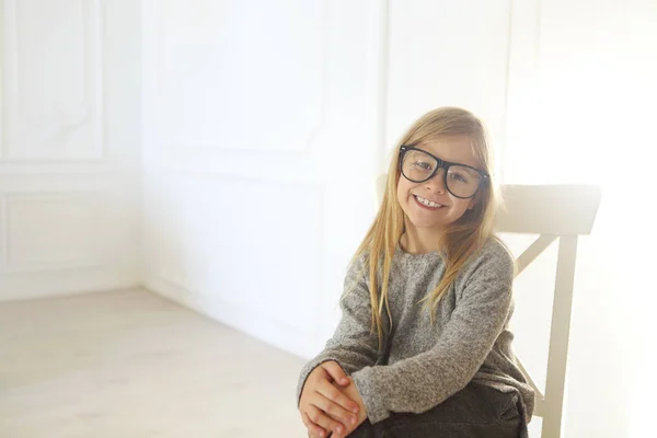 Leende söt liten flicka med svarta glasögon över vita bakgrunds — Stockfoto