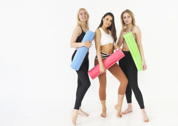 Group of sportive happy women holding yoga mats standing indoors — Stock Photo, Image