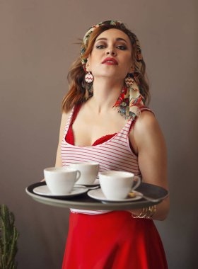 C ile tepsi tutan parlak giysiler giyen güzel genç kadın