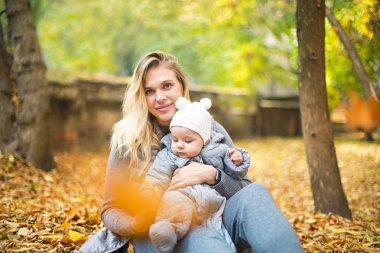 Anne ve onu küçük kızı oynamak sarılma üzerinde Autumn yürümek içinde n