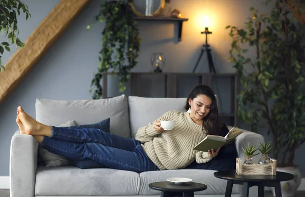 Jeune femme brune heureuse avec un livre portant un pull — Photo