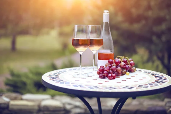 Dos copas y una botella de vino rosa en el viñedo de otoño en mármol —  Fotos de Stock