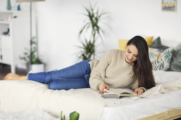Молодая счастливая брюнетка с книгой в свитере — стоковое фото