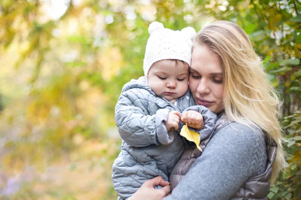 Moeder en haar kleine dochter spelen knuffelen op de herfstwandeling in n — Stockfoto