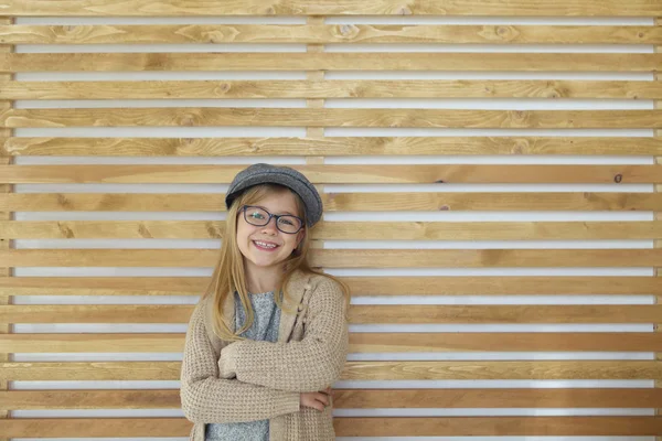 Petite fille mignonne souriante avec des lunettes noires portant une casquette sur — Photo