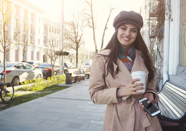 Hübsche Mädchen stehen auf der Straße mit einer Tasse Kaffee neben dem Café w — Stockfoto