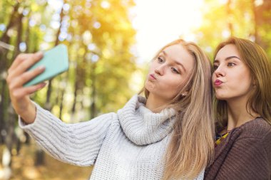 Sonbahar parkında selfie yapan iki güzel genç kadın