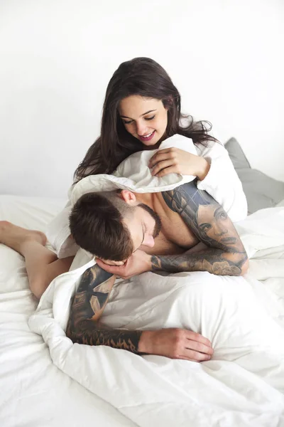 Сексуальная пара улыбается, лежа на кровати вместе — стоковое фото