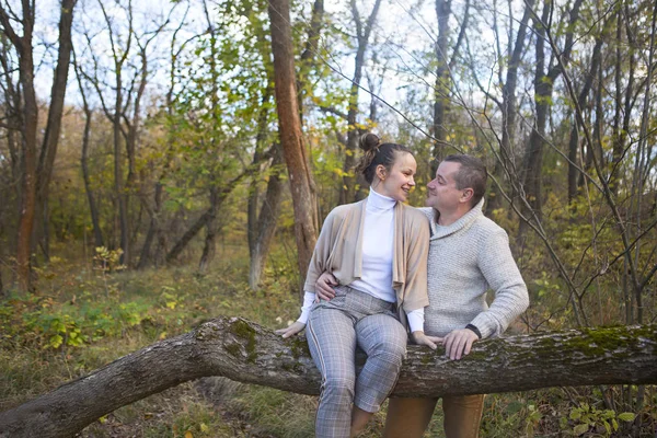Красивая пара, сидящая на дереве в парке и обнимающая — стоковое фото